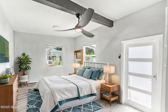 bedroom featuring beamed ceiling, light wood-type flooring, and a ceiling fan