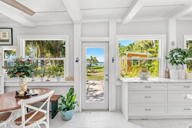 doorway to outside featuring marble finish floor, a wealth of natural light, and beam ceiling