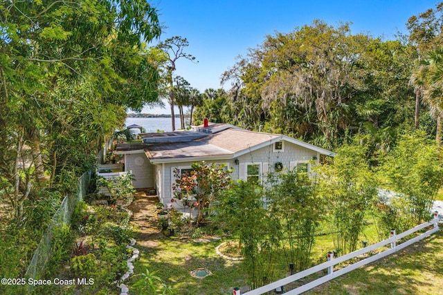 view of side of property with a water view, fence, and solar panels