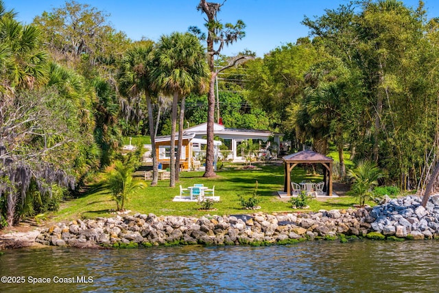 rear view of property with a gazebo, a yard, and a water view