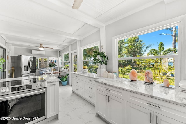 kitchen with ceiling fan, light stone counters, marble finish floor, appliances with stainless steel finishes, and beamed ceiling