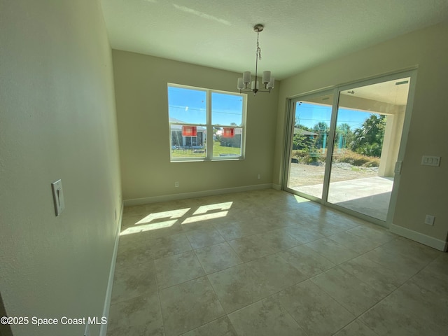 interior space featuring baseboards and a chandelier