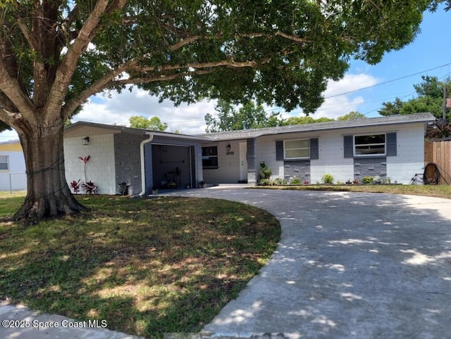 ranch-style home featuring an attached garage, concrete block siding, fence, concrete driveway, and a front lawn