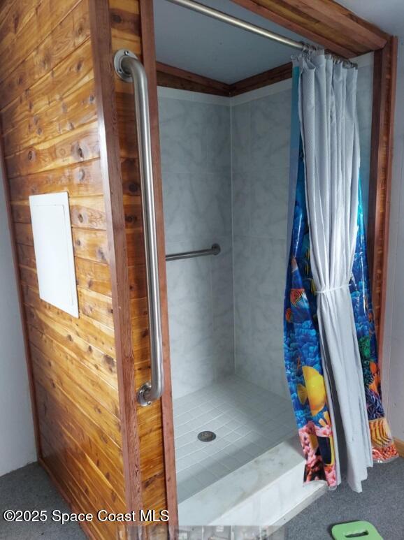 full bathroom with a stall shower and wooden walls