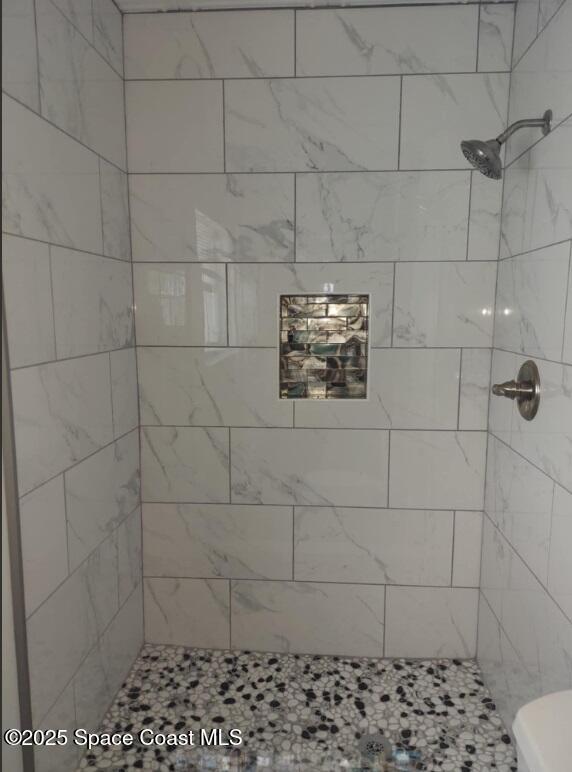 bathroom featuring tiled shower and toilet