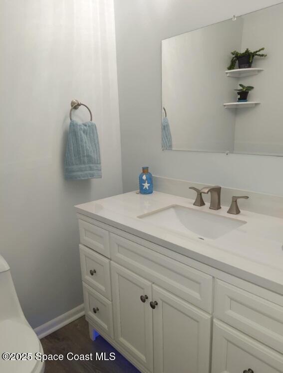 bathroom with toilet, vanity, and baseboards