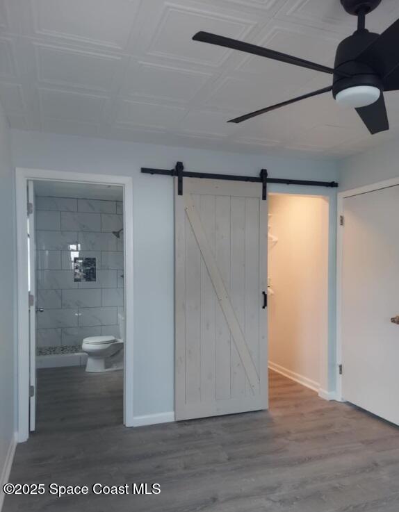 interior space with a stall shower, wood finished floors, toilet, and baseboards