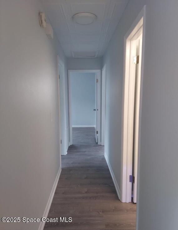 hallway featuring wood finished floors and baseboards