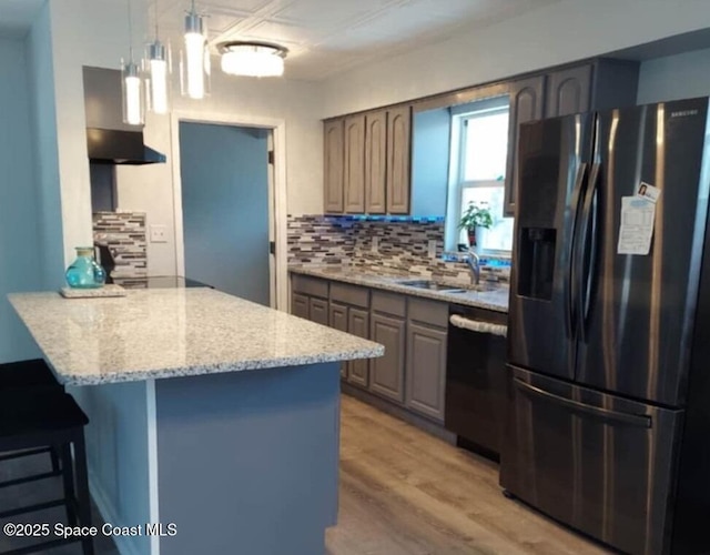 kitchen featuring a peninsula, stainless steel refrigerator with ice dispenser, dishwasher, tasteful backsplash, and a kitchen bar