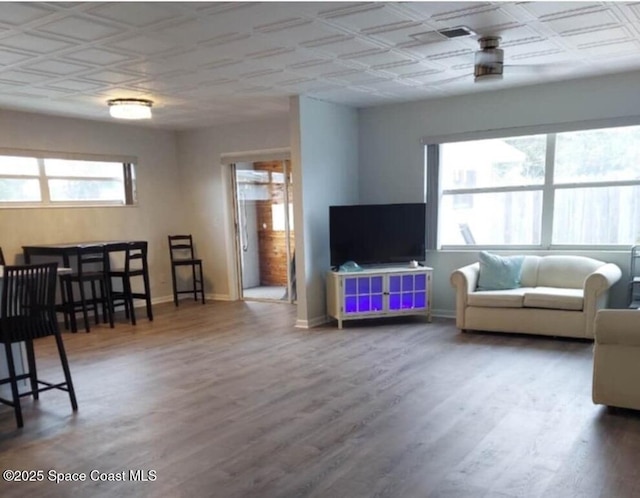 living room with wood finished floors, an ornate ceiling, and baseboards