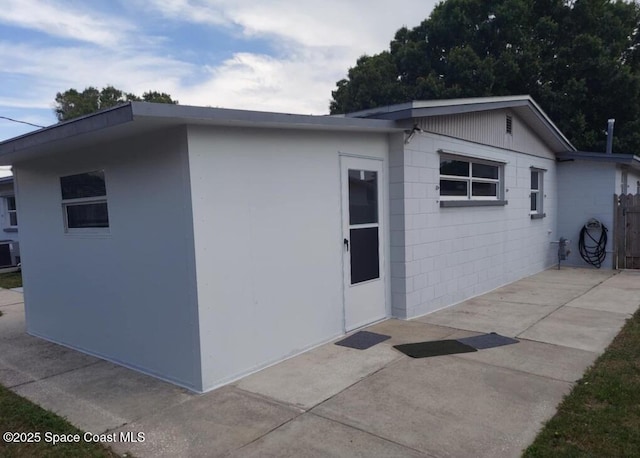 view of side of property featuring a patio area, concrete block siding, and central AC