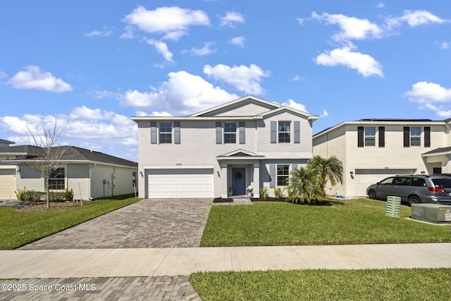 traditional-style house with a garage, a front lawn, decorative driveway, and stucco siding