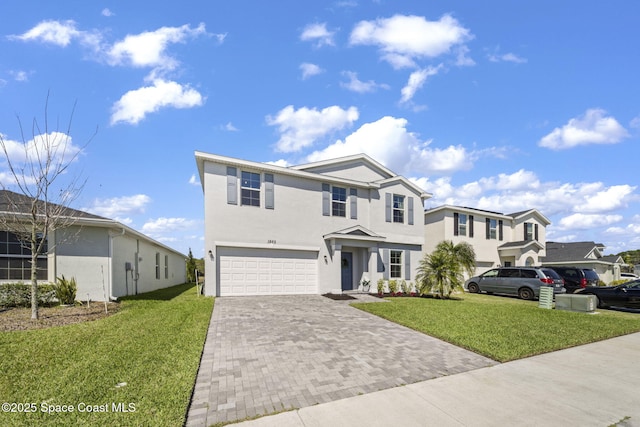 traditional-style home featuring a garage, decorative driveway, a front lawn, and stucco siding