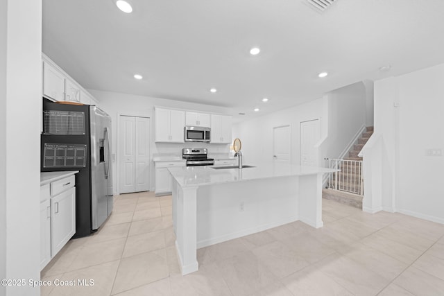 kitchen with stainless steel appliances, recessed lighting, light countertops, and white cabinetry