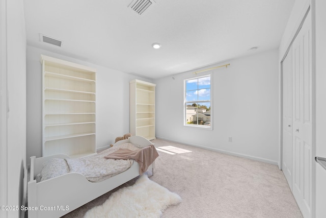 carpeted bedroom with baseboards, visible vents, and a closet