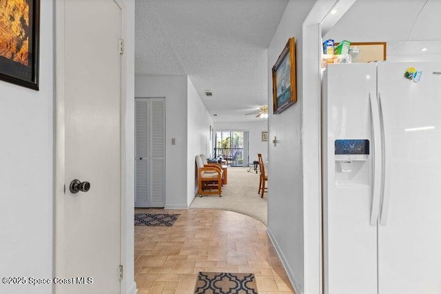 corridor featuring baseboards and a textured ceiling