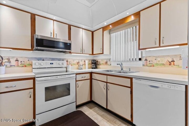 kitchen with white appliances, light countertops, and a sink