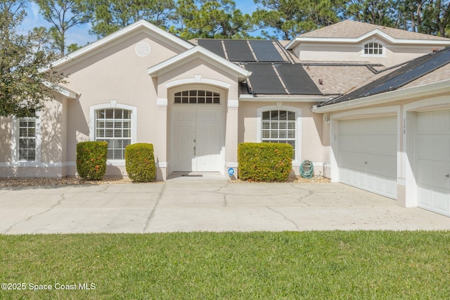 view of front facade featuring a garage, roof mounted solar panels, concrete driveway, and stucco siding