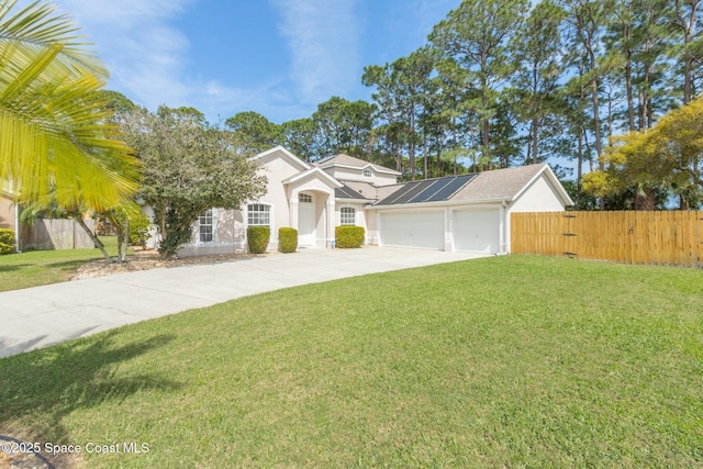 view of front of property with an attached garage, fence, concrete driveway, roof mounted solar panels, and a front yard