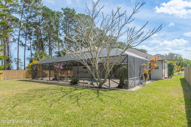 back of property featuring glass enclosure, a lawn, and a fenced backyard