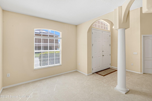 entryway featuring arched walkways, carpet flooring, and decorative columns