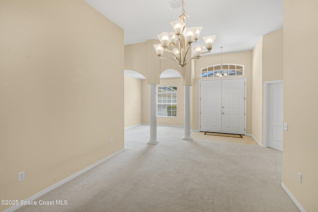 carpeted entrance foyer featuring arched walkways, a notable chandelier, a high ceiling, visible vents, and baseboards