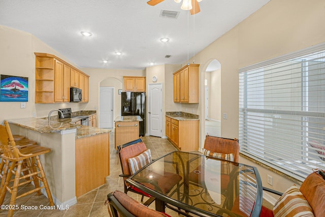 dining space with arched walkways, a textured ceiling, light tile patterned flooring, visible vents, and a ceiling fan