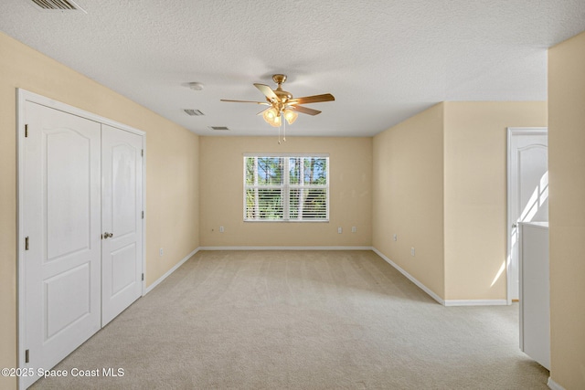 unfurnished room with baseboards, visible vents, a ceiling fan, a textured ceiling, and carpet floors