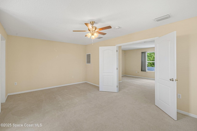 unfurnished room with baseboards, a ceiling fan, visible vents, and light colored carpet