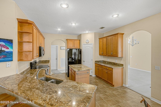 kitchen featuring arched walkways, black appliances, a sink, and open shelves