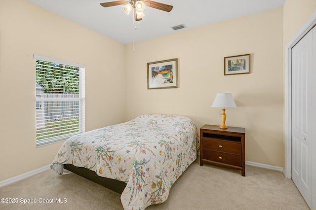 carpeted bedroom with a ceiling fan, a closet, visible vents, and baseboards