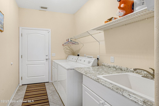 clothes washing area featuring light tile patterned floors, visible vents, cabinet space, washing machine and dryer, and a sink