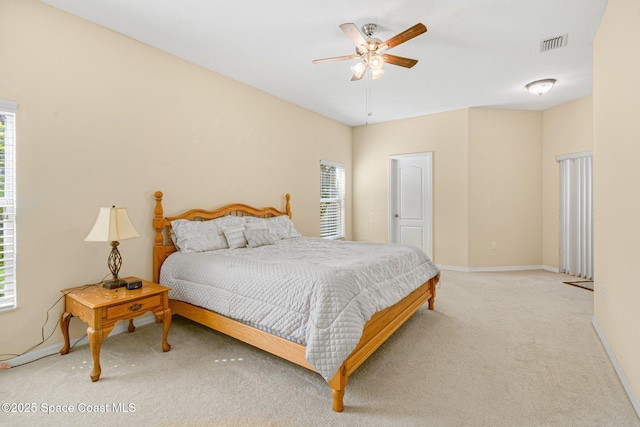 bedroom featuring baseboards, multiple windows, visible vents, and light colored carpet