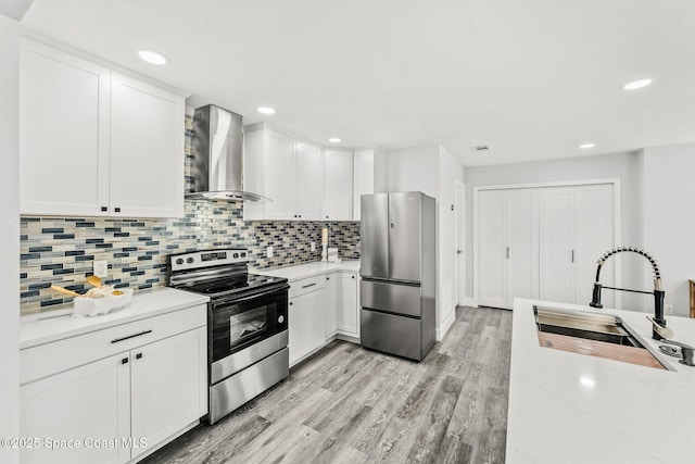 kitchen featuring stainless steel appliances, wall chimney exhaust hood, a sink, and decorative backsplash