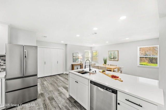 kitchen featuring visible vents, stainless steel appliances, light countertops, light wood-style floors, and a sink