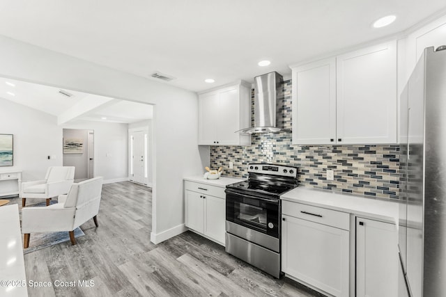 kitchen featuring visible vents, open floor plan, light countertops, wall chimney range hood, and appliances with stainless steel finishes