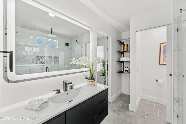 bathroom featuring a marble finish shower, baseboards, and vanity