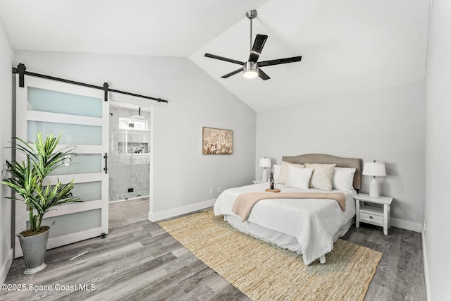 bedroom with vaulted ceiling, a barn door, wood finished floors, and baseboards