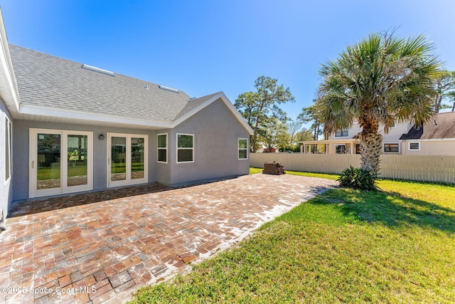 rear view of house with a lawn, roof with shingles, fence, a patio area, and stucco siding