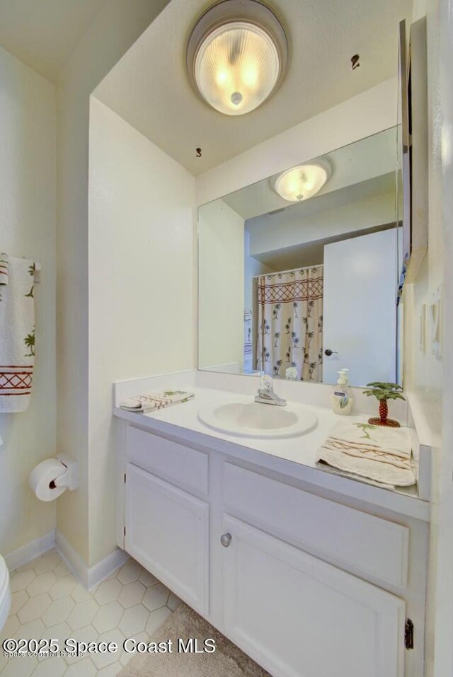 full bath with toilet, vanity, and baseboards