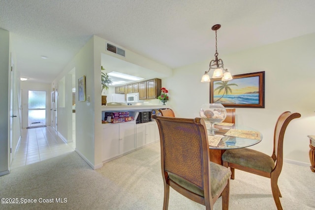 dining room with baseboards, visible vents, a textured ceiling, and light colored carpet