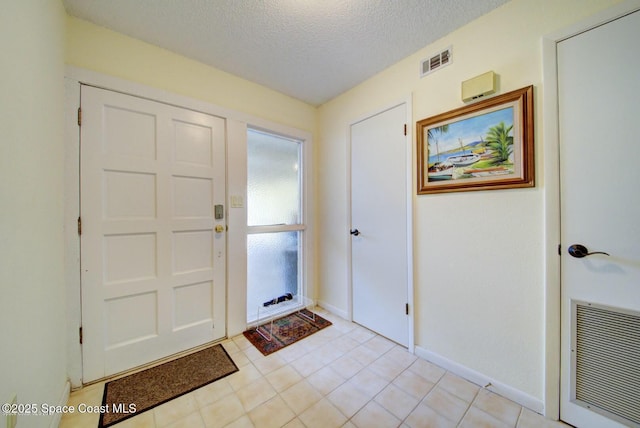 foyer entrance with visible vents, a textured ceiling, and baseboards