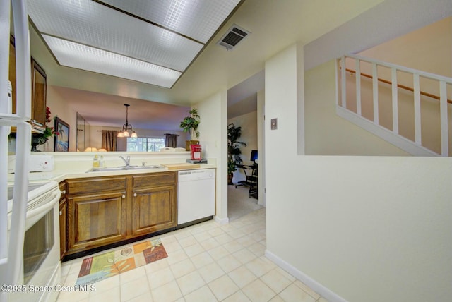 kitchen with white appliances, visible vents, brown cabinets, light countertops, and a sink