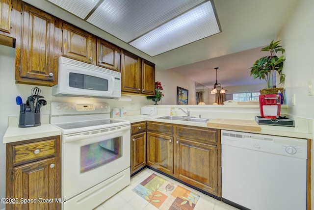 kitchen featuring light countertops, white appliances, a sink, and brown cabinets