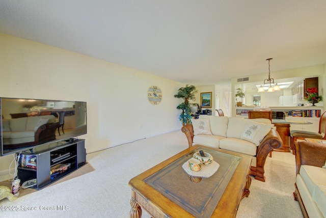 living room featuring carpet floors, visible vents, and a notable chandelier