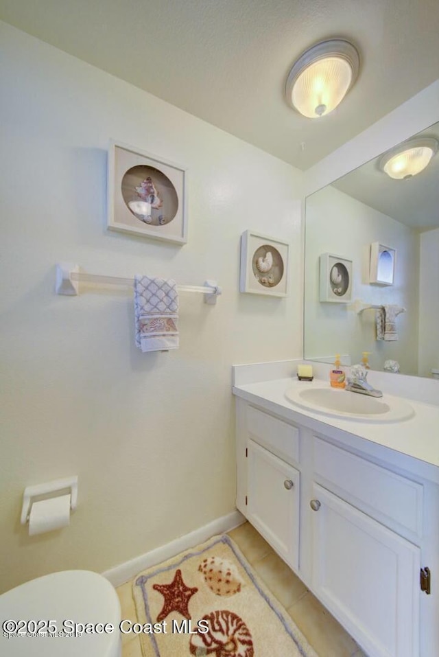 half bath featuring toilet, baseboards, vanity, and tile patterned floors