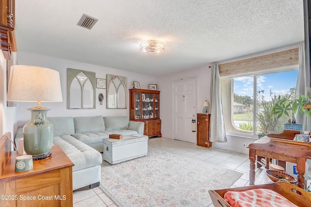 living room featuring visible vents, a textured ceiling, and light tile patterned flooring