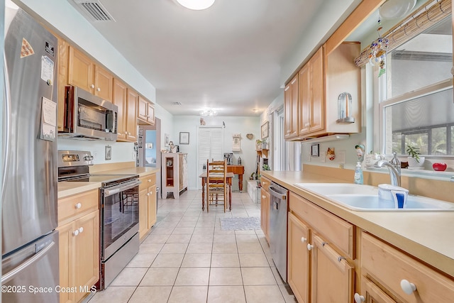 kitchen with light tile patterned floors, stainless steel appliances, light countertops, light brown cabinets, and a sink