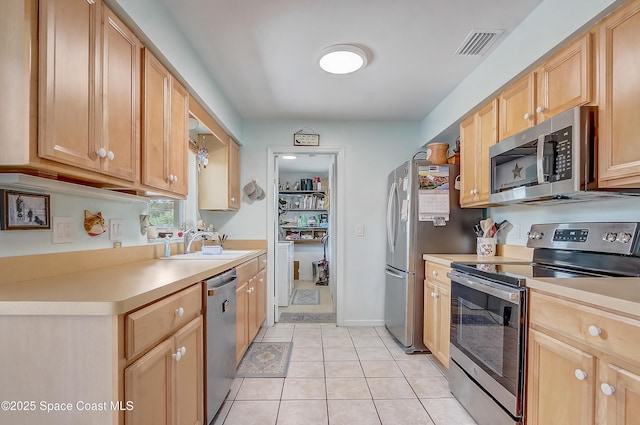 kitchen featuring light tile patterned flooring, stainless steel appliances, a sink, visible vents, and light countertops