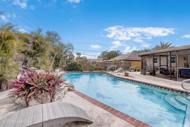 view of swimming pool with a patio area, a fenced backyard, a sunroom, and a fenced in pool